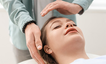 a person receiving a relaxing treatment with hands positioned over their head promoting wellness and tranquility in a calming setting